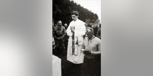 A photo taken during the summer 1952 near Ruhpolding, shows German priest Joseph Ratzinger (C) praying during an open-air mass. 