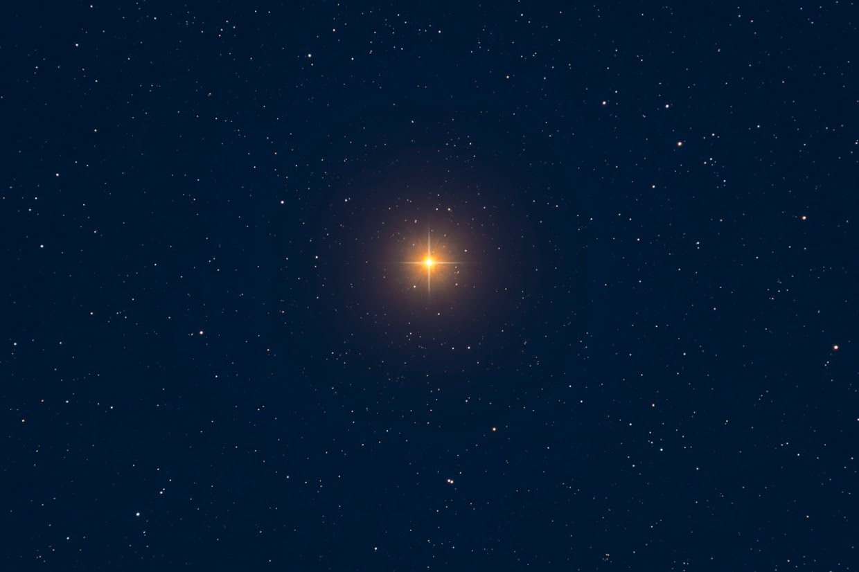 The star, Betelgeuse, shines orange in a blue, star-filled night sky.
